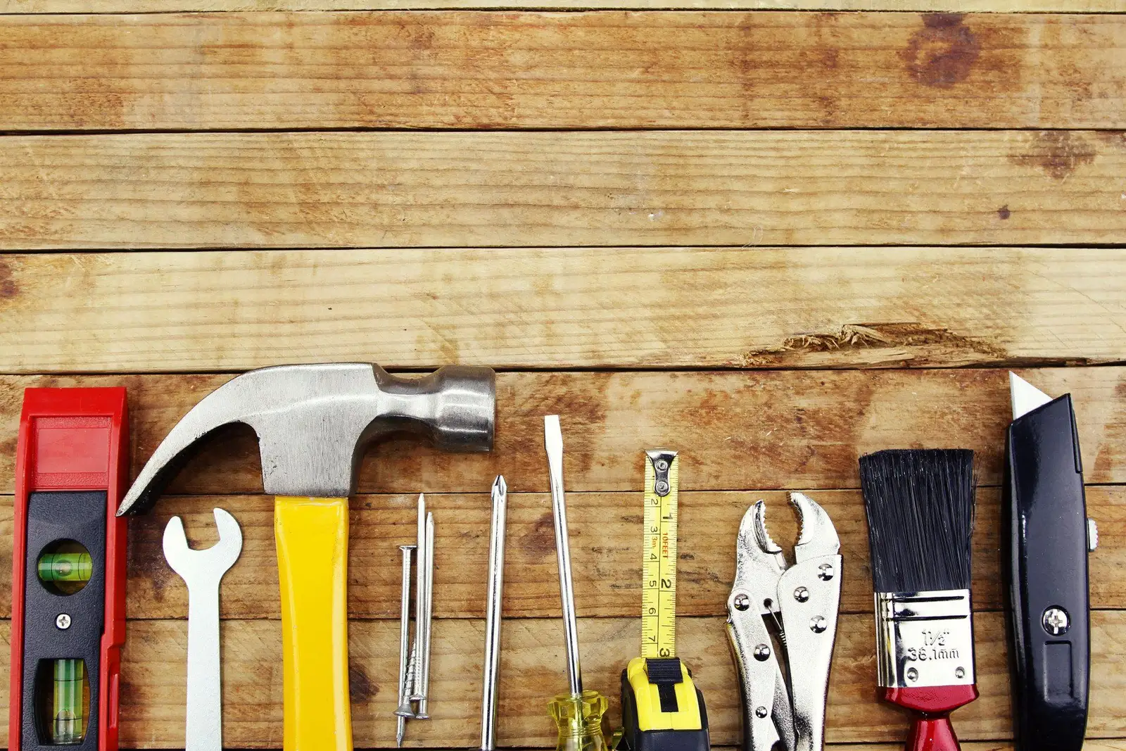 Framing hammer, level and hand tools laid on wood planks