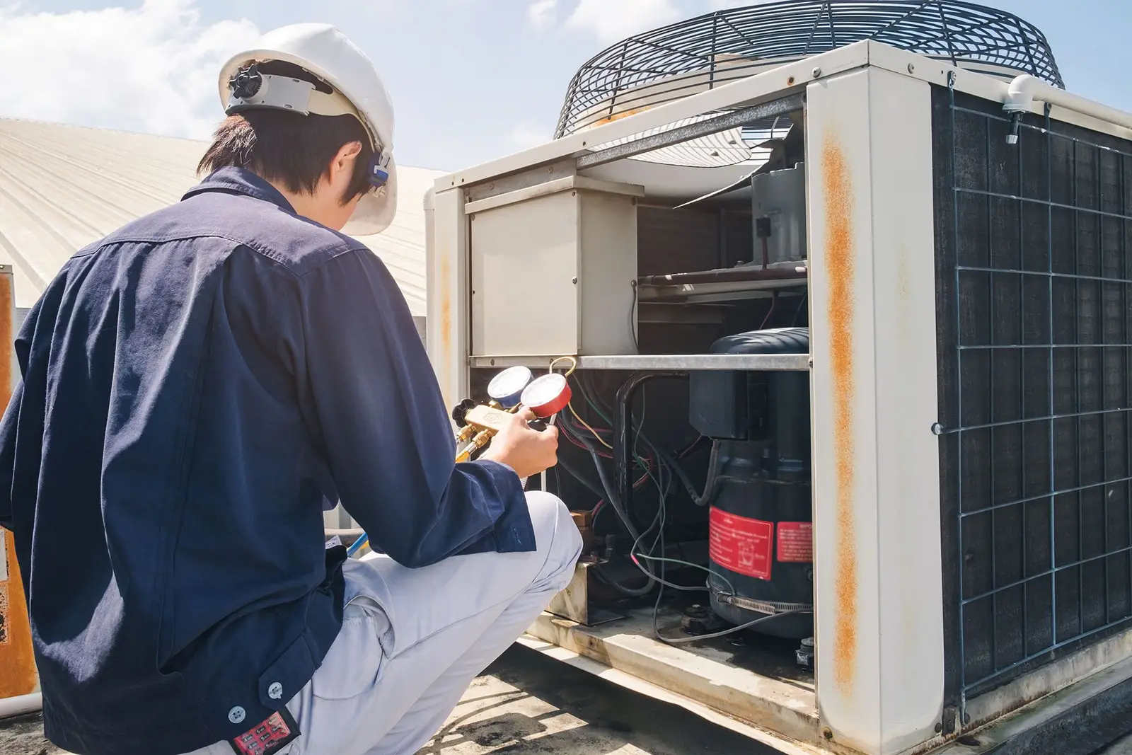 Technician servicing a rooftop commercial HVAC unit
