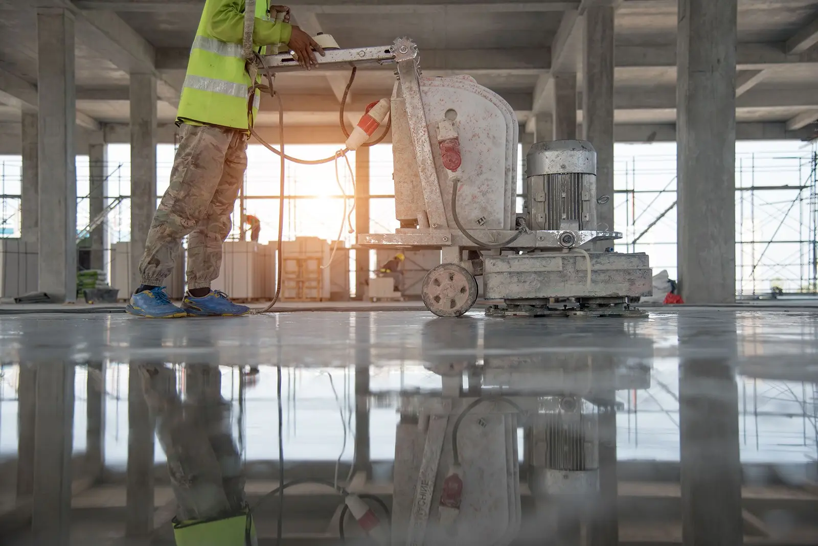 Worker running a concrete grinder over a polished commercial floor